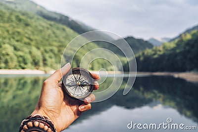 Lost woman on the mountain, orienting herself with a compass. Find a solution Stock Photo