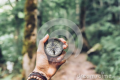 Lost woman on the mountain, orienting herself with a compass. Find a solution Stock Photo