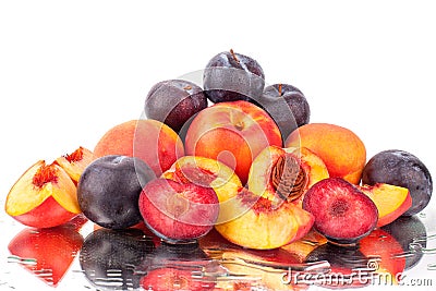 A lot of bright fruits, whole and cut peaches and plums on a mirror white background in water drops isolated Stock Photo