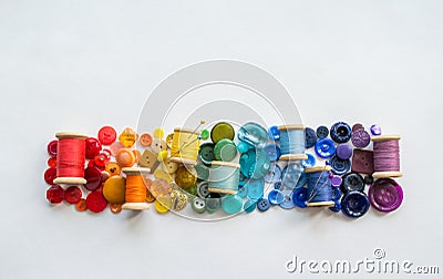 A lot of buttons and reels with colorful threads, laid out on a white background in the colors of the rainbow. Copy space Stock Photo