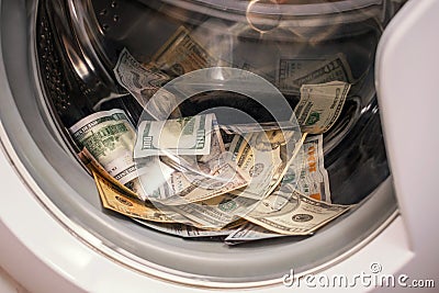 A lot of cash dollars is washed in the drum of a washing machine. Many banknotes are inside Washer. The concept of not legal money Stock Photo