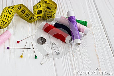 A lot of color threads, meter, buttons and pins on white wooden Stock Photo