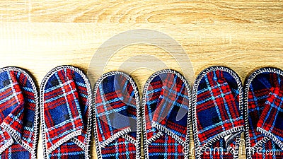 A lot of colorful comfortable, cushioned, checkered disposable slippers are on the wooden floor. Top view. Concept of hospitality Stock Photo