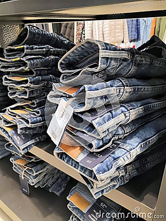 Lot of different color striped long sleeve,blue jeans shirts are neatly stacked in a row on the store shelves Editorial Stock Photo