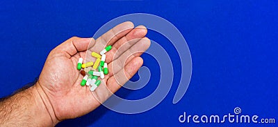 A lot of different pills in a male hand close-up. Blue blurred background. Pharmaceutical business concept. Healthcare industry. Stock Photo