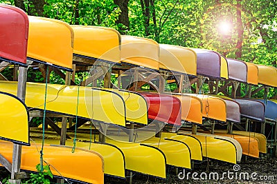 Lot of multi colored kayaks on the bank of the river, in summer or spring time. Colorful canoes or kayaking boats parked in the Stock Photo