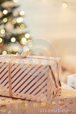 A lot of packing handmade gift boxes lying on the table near Christmas tree in the midst of golden lights, glowing garland, candle Stock Photo