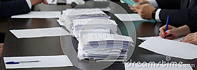 A lot of papers or ballots are on the table, where officials or businessmen are sitting. Counting of votes. Reportage. Panorama Stock Photo