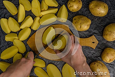 A lot of potatoes on table and on a cutting board. Potatoes, sliced on a cutting board. Potato cleaning on the table. Knife for sl Stock Photo