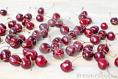 A lot of red berries of sweet cherry scattered on light wooden table close up, bunch of ripe cherry berries on white background Stock Photo