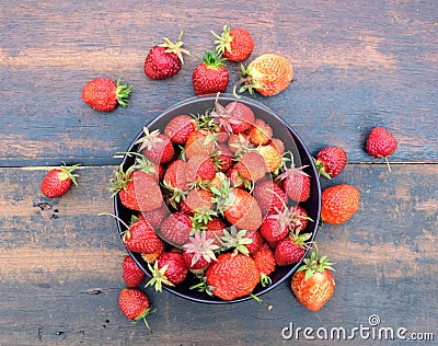 Lot of ripe appetizing strawberries in the round bowl on vintage wooden table closeup Stock Photo