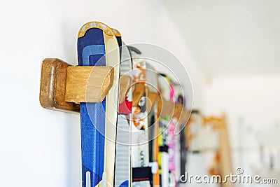 Lot of ski hanged on customized wooden wall mount at garage for seasonal storage. Extreme winter sport equipment handling at home Stock Photo