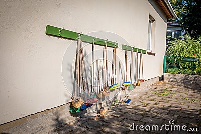 Lot of small coloured brooms hang on the outside wall of a kindergarten Stock Photo