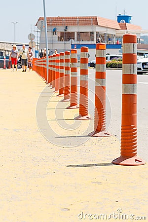 Lot of striped orange reflictive traffic bollards placed in row for safety and security between roads and pedestrian Stock Photo