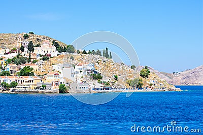 A lot of tiny colorful houses on the rocky shore of Mediterrenean sea on Simy greek island in sunny summer day, tourism Stock Photo