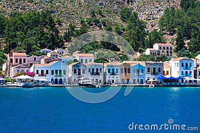 A lot of tiny colorful houses on the rocky shore of Mediterrenean sea on Simy greek island in sunny summer day, Stock Photo