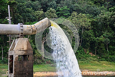 Lot of water gushing out of the big metal pipe to the lake, pump water fill in reservoir Stock Photo