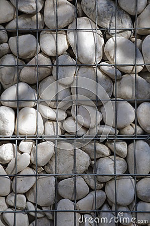 A lot of white polished pebbles behind a metal grid Stock Photo