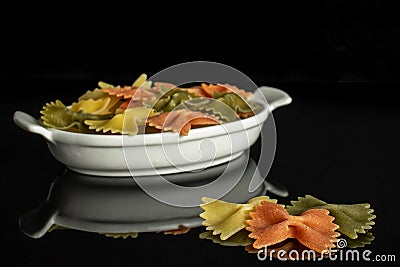 Raw farfalle tricolore isolated on black glass Stock Photo