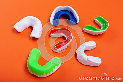 Lots of boxing protective mouthguards on orange background, concept Stock Photo