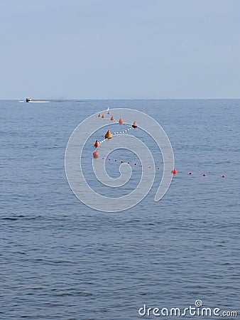 Lots of mooring buoys floating on water in marina. Small boat visible at the top of image. Calm water with small waves Stock Photo