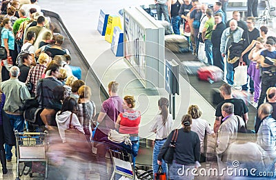 Lots of people getting luggage at airport. Stock Photo