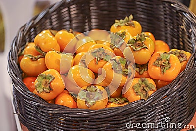 Lots of persimmon in basket at bazaar. agriculture farm full of organic vegetables. Pile of ripe persimmon in the store. Stock Photo