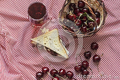 Lots of sour cherries and a toast bread sandwich on a plaid picnic blanket, still life photography Stock Photo