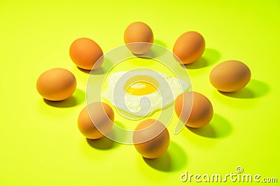 Lots of brown eggs with one fried egg in the center in light green background Stock Photo
