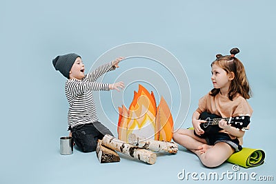 Loud boy and quiet girl with guitar are sitting next to fake campfire Stock Photo