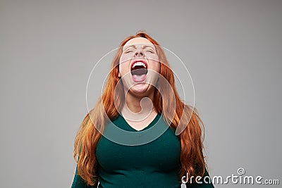 Loudly screaming redhead woman expressing negative emot Stock Photo
