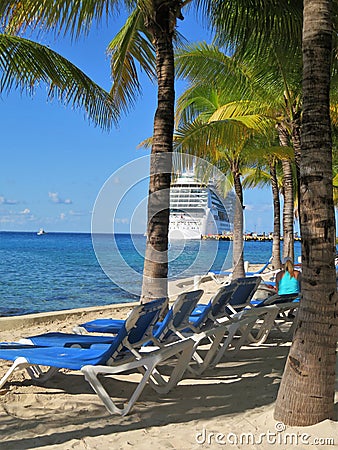 Lounge chairs on the beach in Cozumel, Mexico with a cruise ship in the background; Editorial Stock Photo