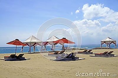 Lounger chairs and parasols on a sand beach in Bali Stock Photo