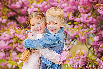 Love is in the air. Kids in love pink cherry blossom. Romantic babies. Couple kids walk sakura tree garden. Tender love Stock Photo