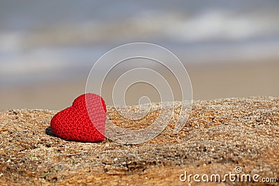 Love on the beach, red knitted heart on blue sea background Stock Photo