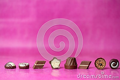 Love chocolate - sweet chocolates in a line on a pink background Stock Photo