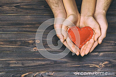 Love, family concept. Close up of man and woman hands holding red rubber heart together toned, vintage Stock Photo