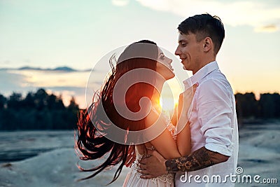 Love kiss and hugs in love couples at sunset in the evening sun, a walk through the mountains and hills. Sensual and gentle loving Stock Photo