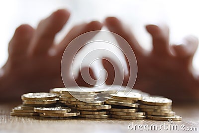 Greedy hand grabbing or reaching out for pile of golden coins. Close up - Concept for tax, fraud and greed Stock Photo