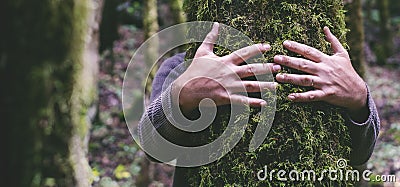 Love for nature concept with man hands hugging bonding green musk trunk tree in the forest woods. Environment and protection. Stock Photo