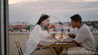 Love pair enjoying food at balcony with sunset city view. Couple celebrating Stock Photo