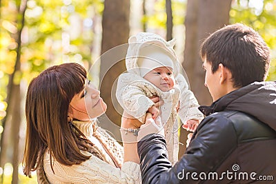 Love, parenthood, family, season and people concept - smiling couple with baby in autumn park Stock Photo