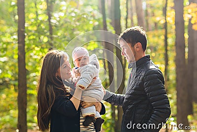 Love, parenthood, family, season and people concept - smiling couple with baby in autumn park Stock Photo