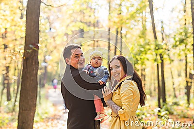 Love, parenthood, family, season and people concept - smiling couple with baby in autumn park Stock Photo