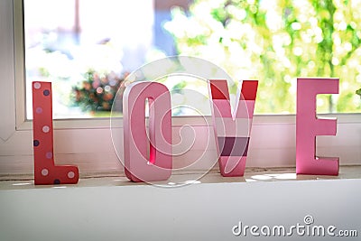 love in pink letters in front of the window Stock Photo