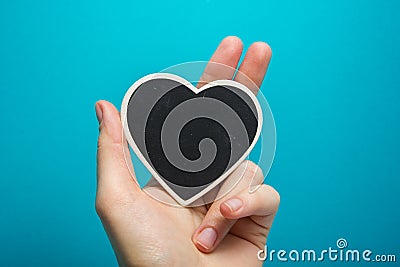 Love sign. Black board heart in woman hands on blue background Stock Photo