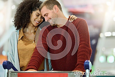 Love, travel and couple at airport with luggage, bonding and affection. Romance, diversity and care of happy man and Stock Photo