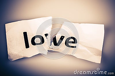 Love word on torn paper - broken love Stock Photo