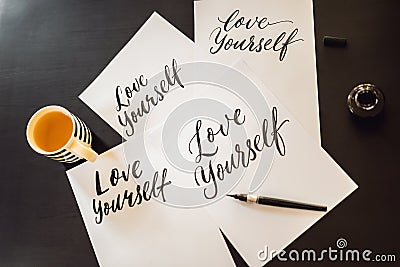 Love yourself. Calligrapher Young Woman writes phrase on white paper. Inscribing ornamental decorated letters Stock Photo