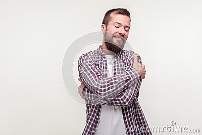 Love yourself. Portrait of smiling confident bearded man embracing himself with satisfied pleased expression. white background Stock Photo